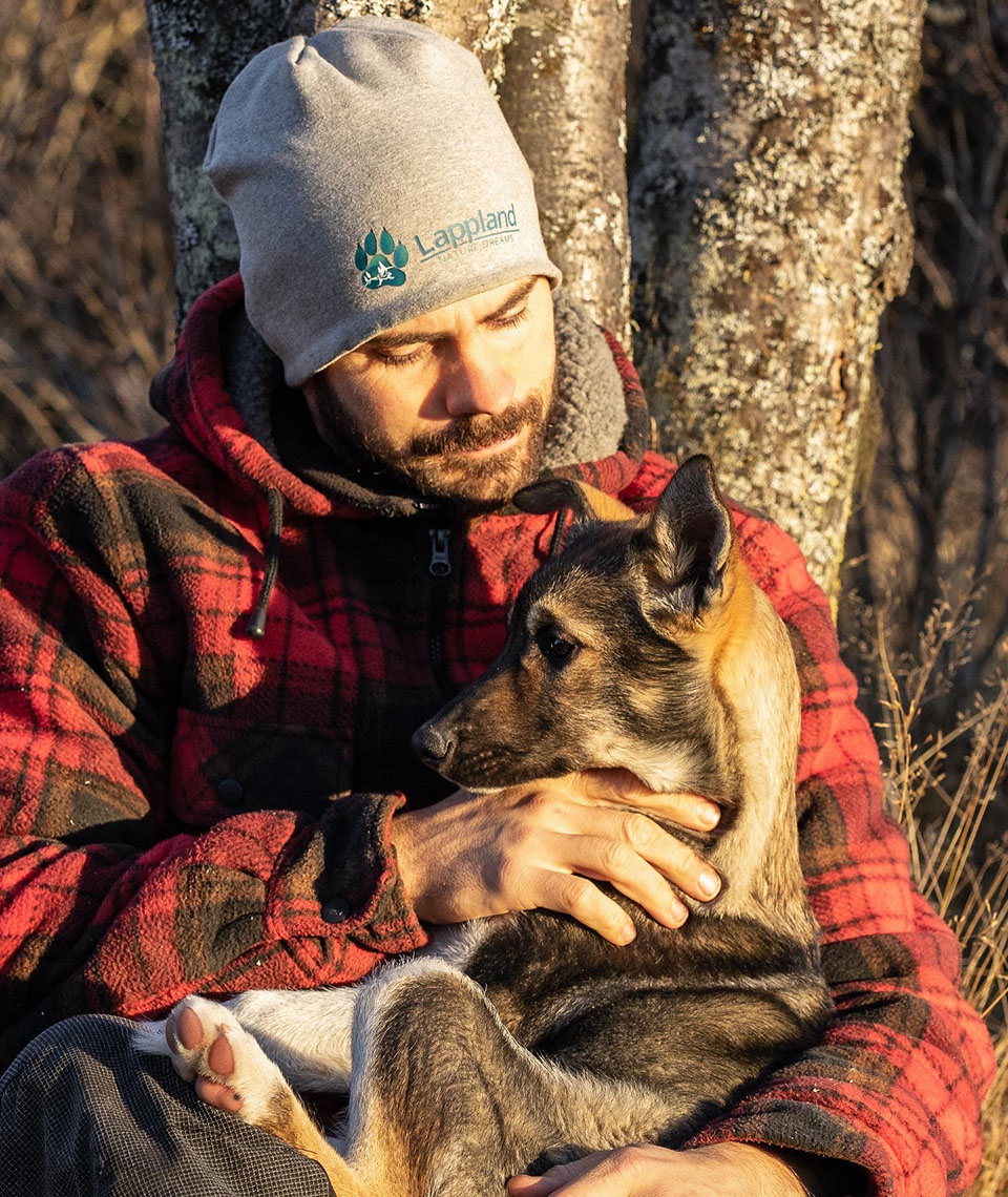 Raphael leaning against a tree with a small dog on his lap.